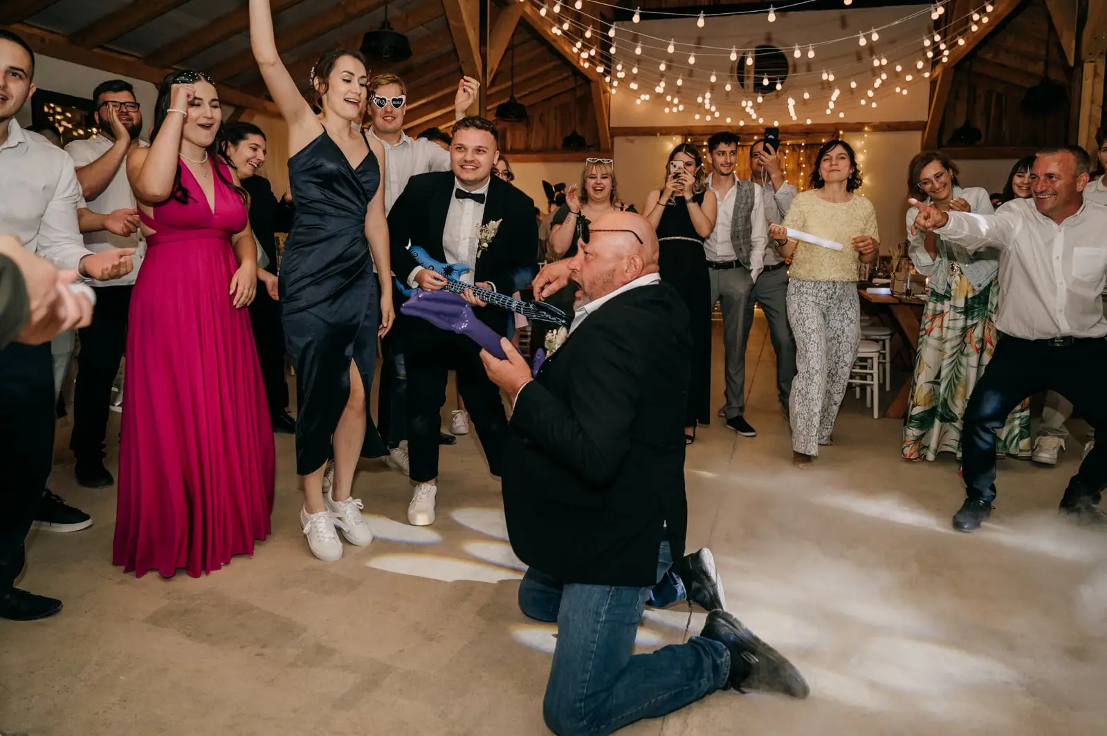 Felfújható gitárral táncoló vendégek az esküvői buli táncterén